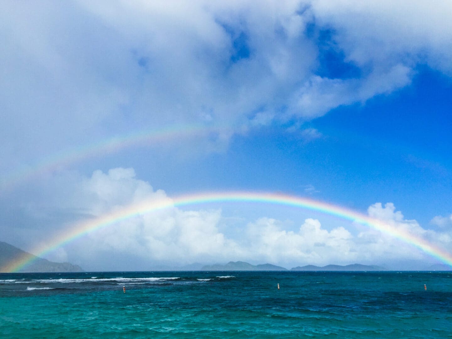A rainbow over the ocean with a boat in it.